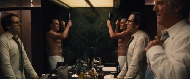 Wide shot frame from Battle of the Sexes — standing, table, dialogue