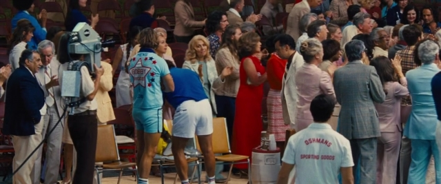 Wide shot frame from Battle of the Sexes — standing, shirt, person