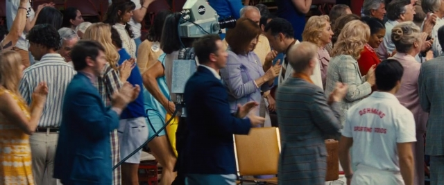 Wide shot frame from Battle of the Sexes — standing, dialogue, suit