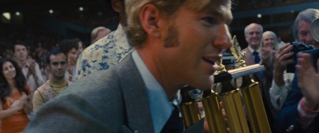 Wide shot frame from Battle of the Sexes — standing, suit, face