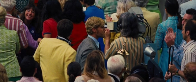 Wide shot frame from Battle of the Sexes — standing, room, dialogue