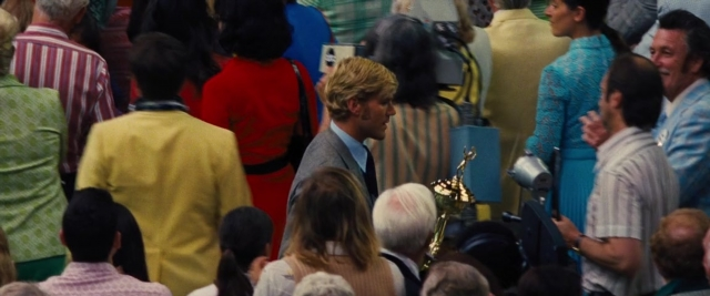 Wide shot frame from Battle of the Sexes — standing, room, dialogue