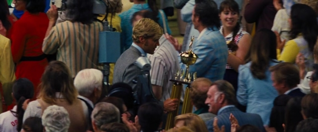 Wide shot frame from Battle of the Sexes — room, dialogue, suit