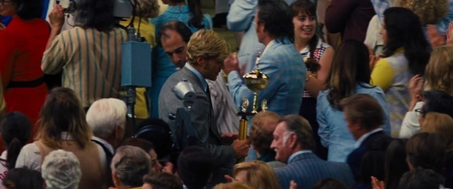 Wide shot frame from Battle of the Sexes — standing, room, dialogue