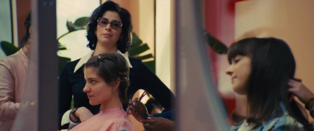 Wide shot frame from Battle of the Sexes — sitting, standing, room
