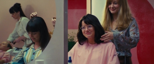 Wide shot frame from Battle of the Sexes — sitting, standing, mirror