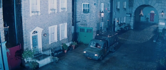 Wide shot frame from 101 Dalmatians — door, street, car
