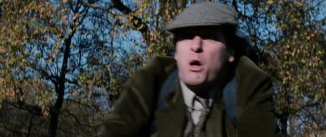 Medium shot frame from 101 Dalmatians — standing, dialogue, hat