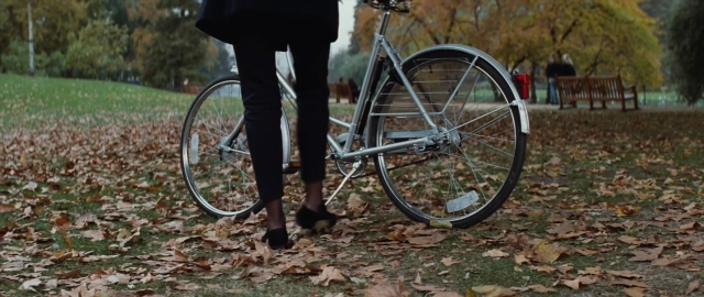 Wide shot frame from 101 Dalmatians — standing, bicycle, bench
