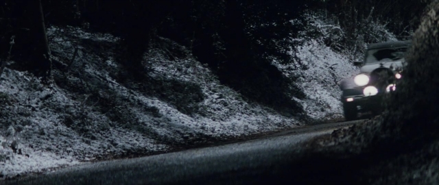 Wide shot frame from 101 Dalmatians — street, car, night