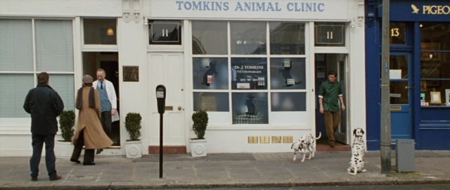 Wide shot frame from 101 Dalmatians — standing, door, street