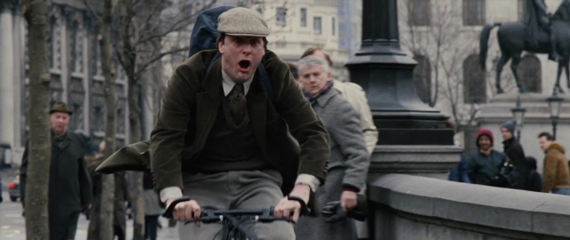 Wide shot frame from 101 Dalmatians — walking, street, hat