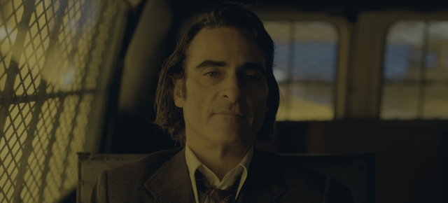 Medium shot frame from Joker: Folie à Deux — sitting, car, suit