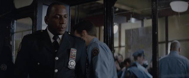 Wide shot frame from Batman Begins — standing, door, uniform
