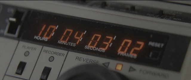 Wide shot frame from Dogman — digital clock