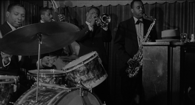 Wide shot frame from Anatomy of a Murder — standing, suit, tie