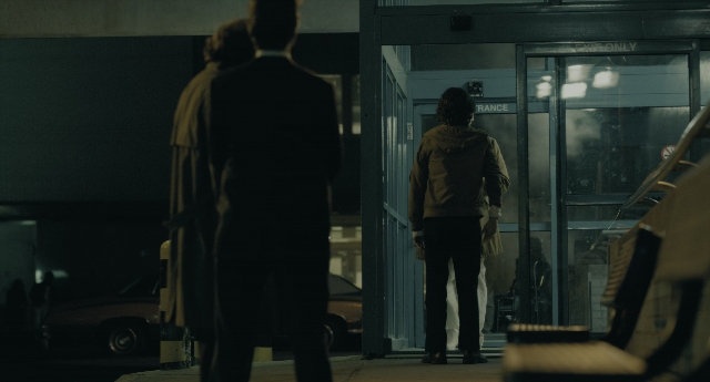 Wide shot frame from Joker — standing, door, coat