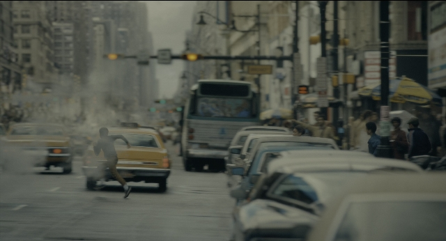 Wide shot frame from Joker — walking, street, car