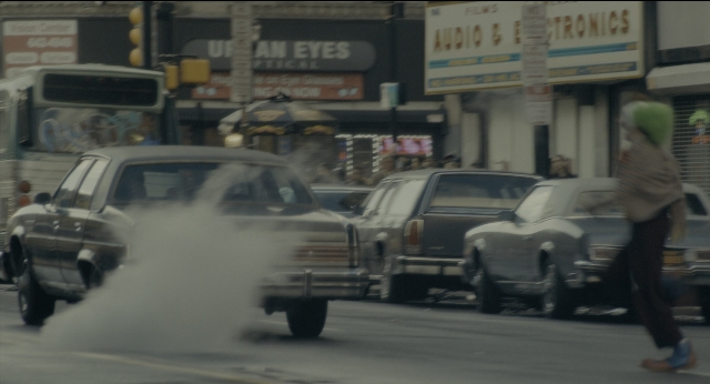 Wide shot frame from Joker — walking, street, car