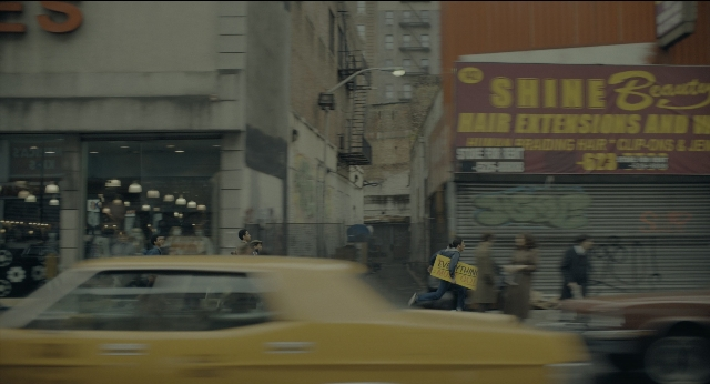 Wide shot frame from Joker — walking, street, car