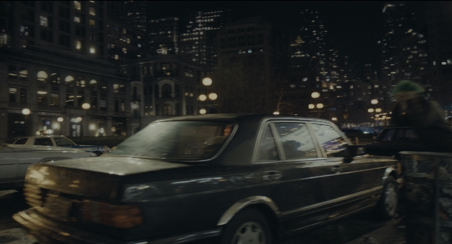 Wide shot frame from Joker — walking, street, car