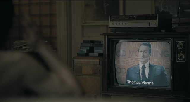 Wide shot frame from Joker — room, suit, television
