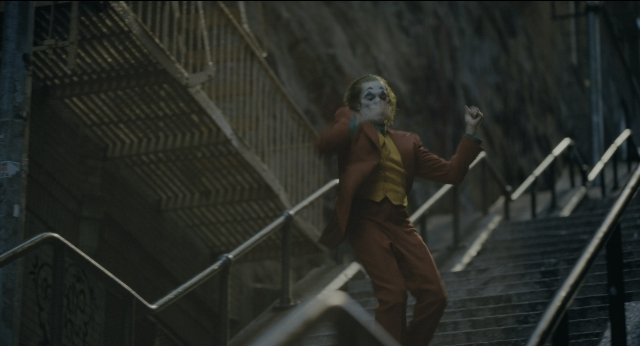 Wide shot frame from Joker — walking, hand, suit