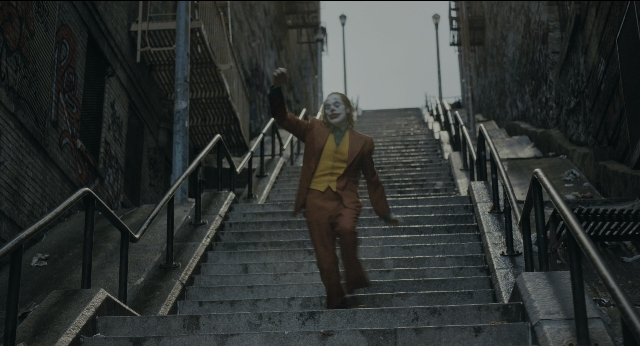 Wide shot frame from Joker — walking, suit, tie