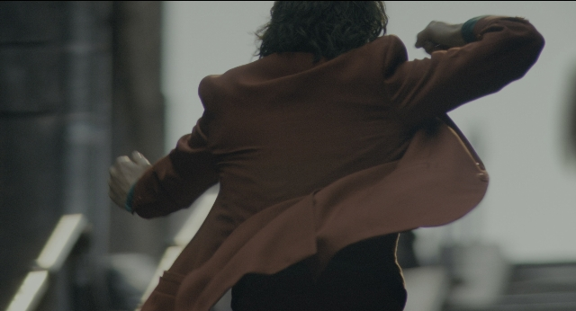 Wide shot frame from Joker — standing, room, coat