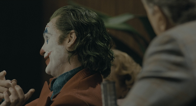 Wide shot frame from Joker — sitting, room, suit