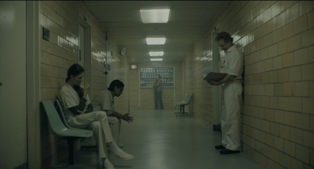 Medium shot frame from Joker — sitting, book, standing