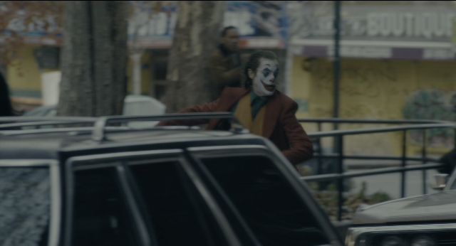 Wide shot frame from Joker — standing, car, suit