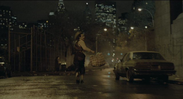 Wide shot frame from Joker — walking, street, car