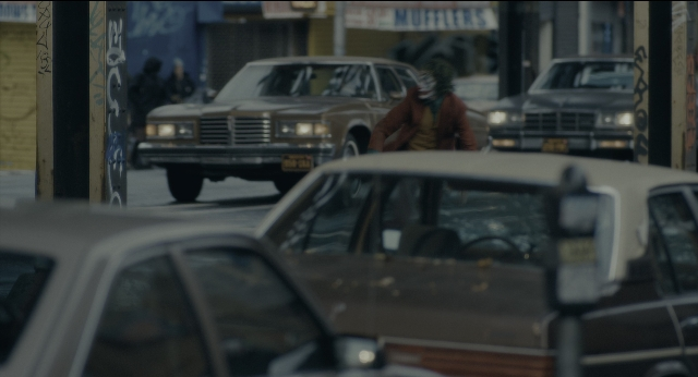 Wide shot frame from Joker — walking, street, hat