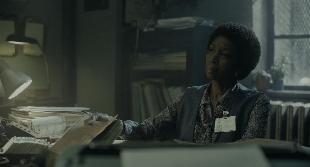 Wide shot frame from Joker — sitting, book, office
