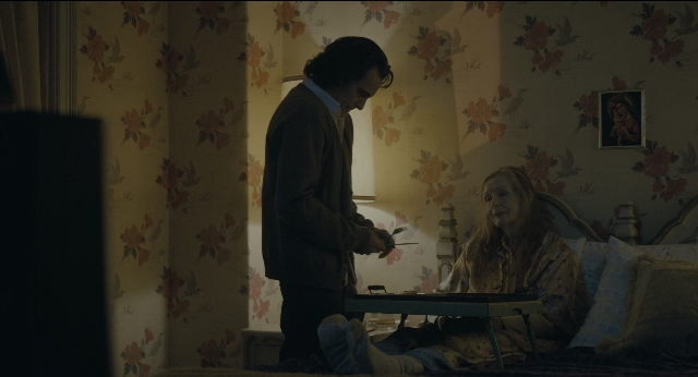 Wide shot frame from Joker — sitting, standing, room