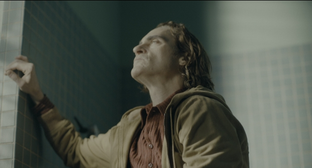 Wide shot frame from Joker — standing, room, shirt