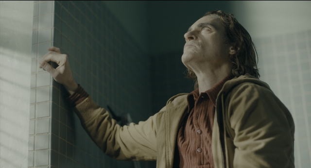 Wide shot frame from Joker — standing, room, shirt