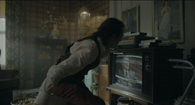 Wide shot frame from Joker — sitting, room, suit