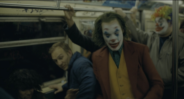 Wide shot frame from Joker — suit, tie, face