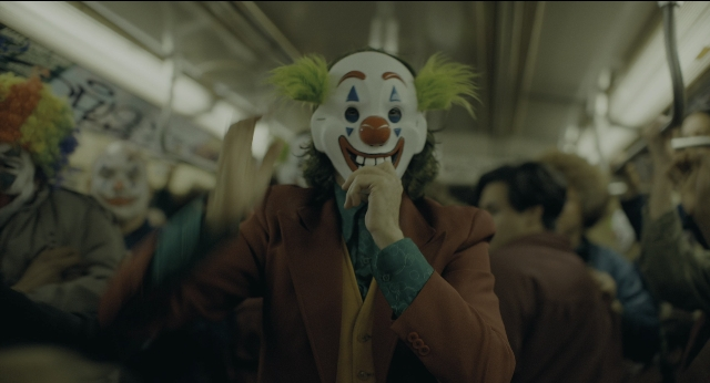 Wide shot frame from Joker — suit, face, train