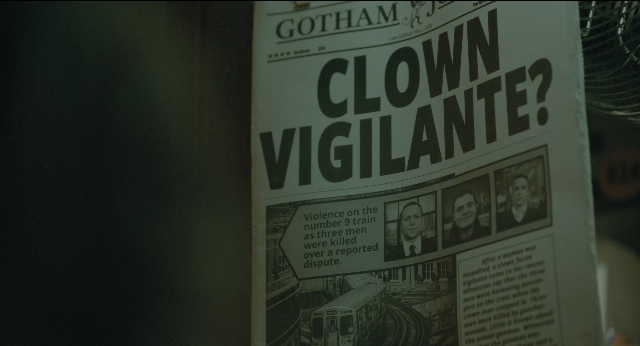 Wide shot frame from Joker — newspaper, poster, train