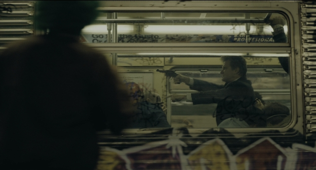 Wide shot frame from Joker — standing, hand, gun