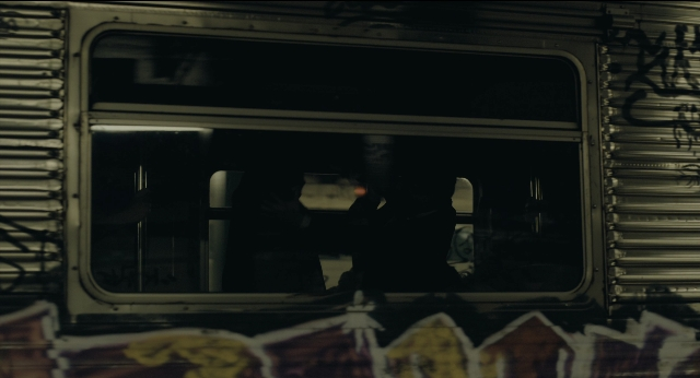 Wide shot frame from Joker — sitting, standing, car