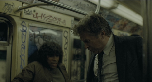 Wide shot frame from Joker — sitting, suit, tie