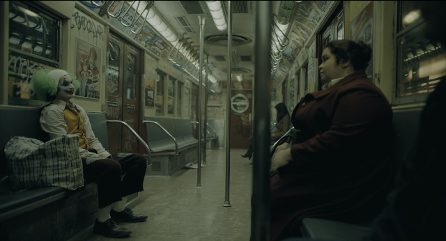 Wide shot frame from Joker — sitting, coat, face