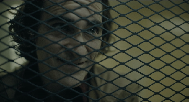Close-up frame from Joker — room, door, face