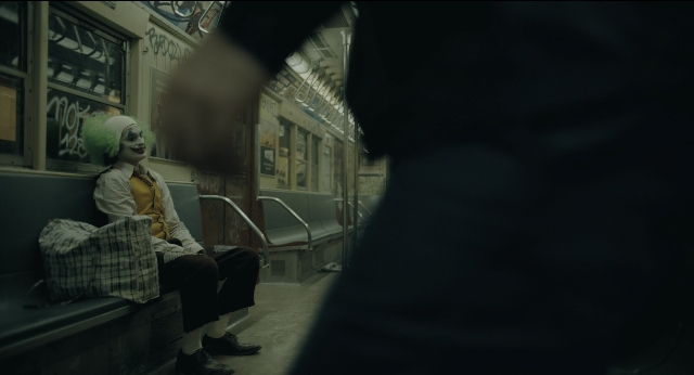 Wide shot frame from Joker — sitting, hand, shirt