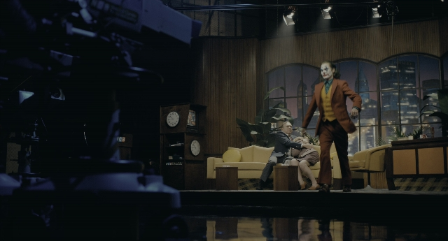 Wide shot frame from Joker — sitting, standing, suit