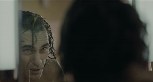 Medium shot frame from Joker — room, mirror, face